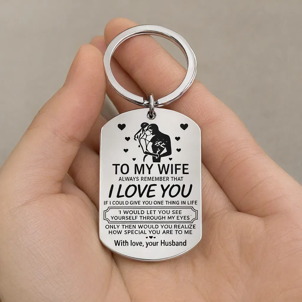 Hand holding a silver engraved steel keychain gift for wife with a love message