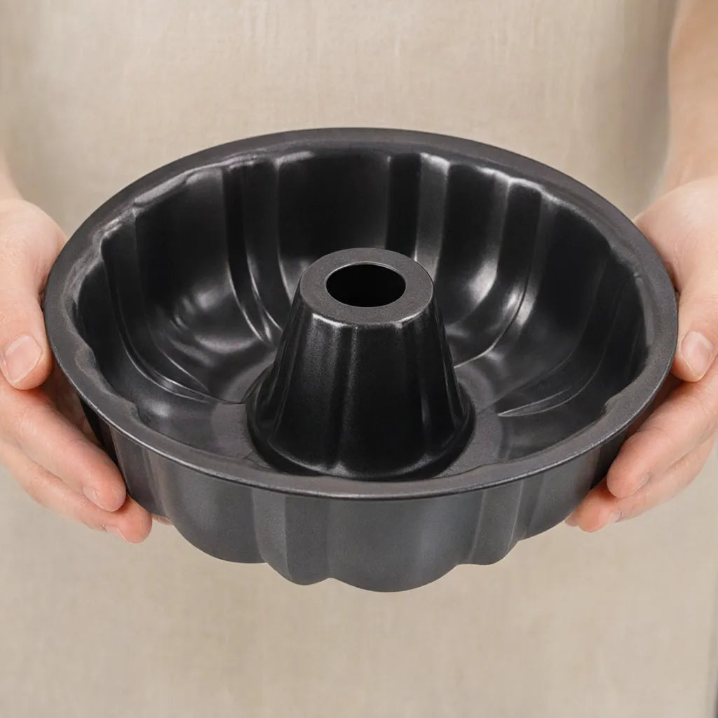 Hands holding a black non-stick fluted ring cake pan, a bundt mold for ring breads