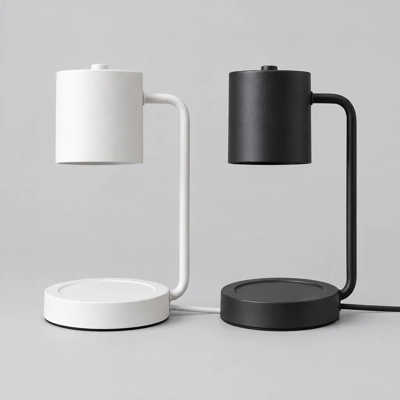 One white and one black candle warmer lamp side by side on a grey surface