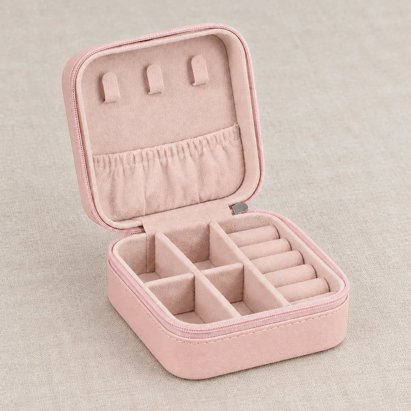 Pink mini travel jewelry case, open and empty, on a linen surface