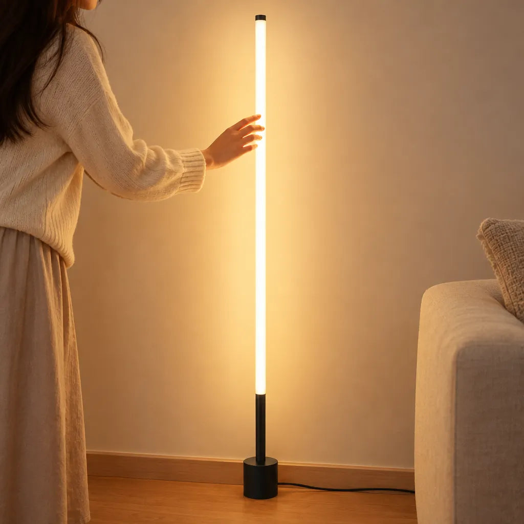 Lampadaire LED mince allumé à côté d'un canapé