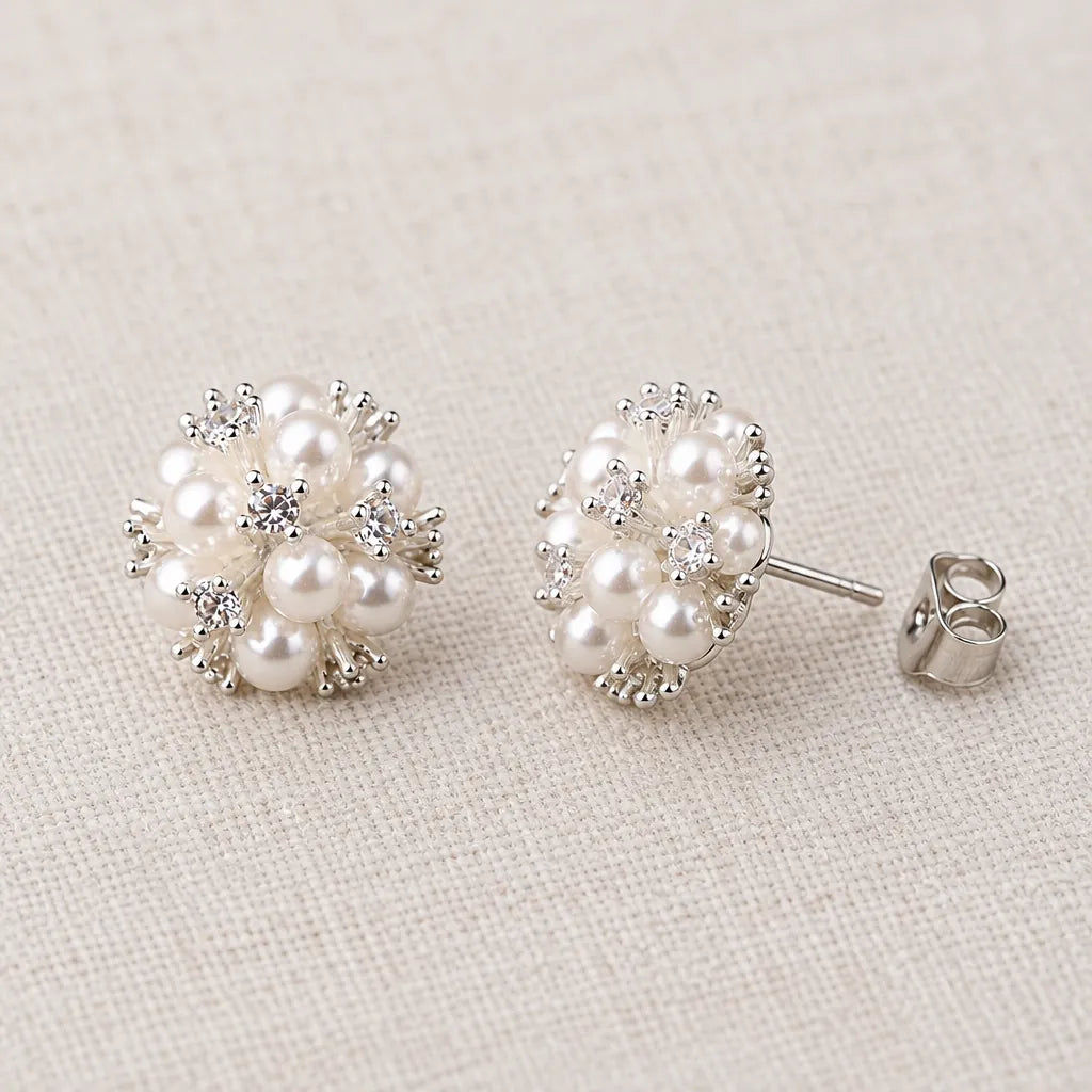 One pair of pearl stud earrings with push-on backs on a linen surface