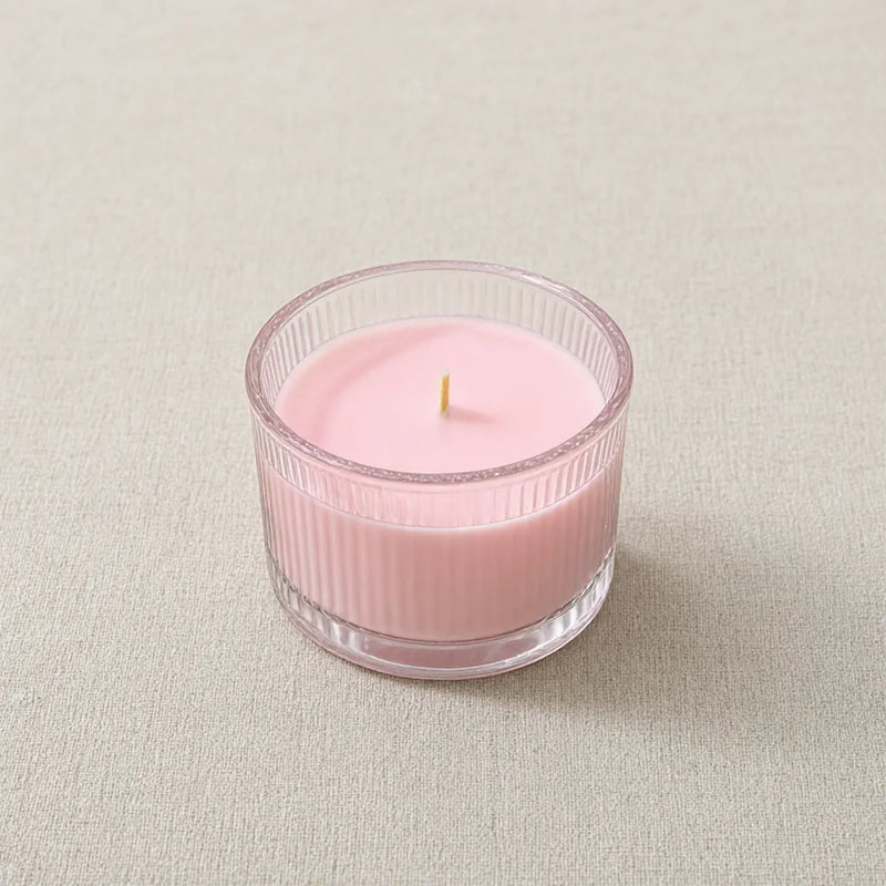 One pink ribbed glass candle jar with a wooden wick