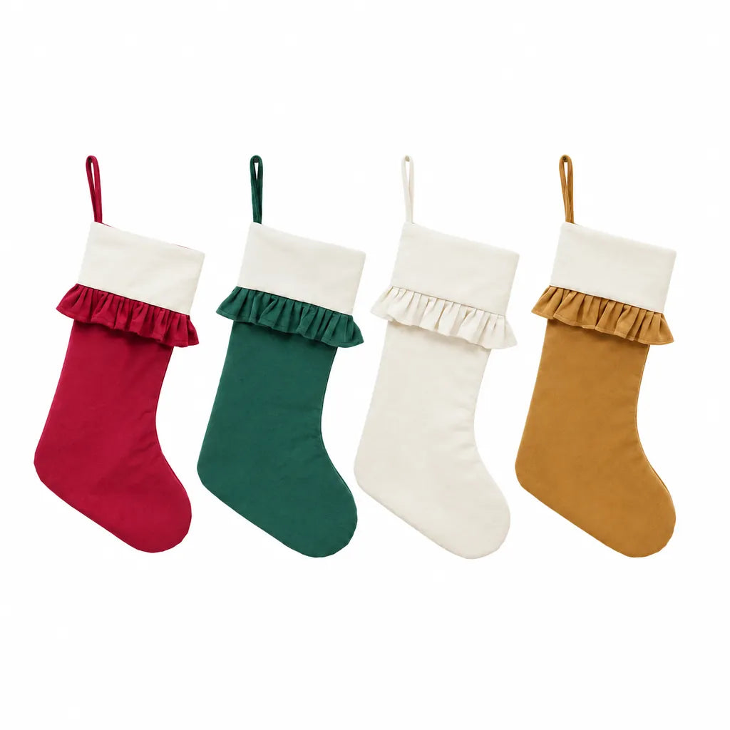 Four velvet Christmas stockings in red, green, ivory and gold on a white background