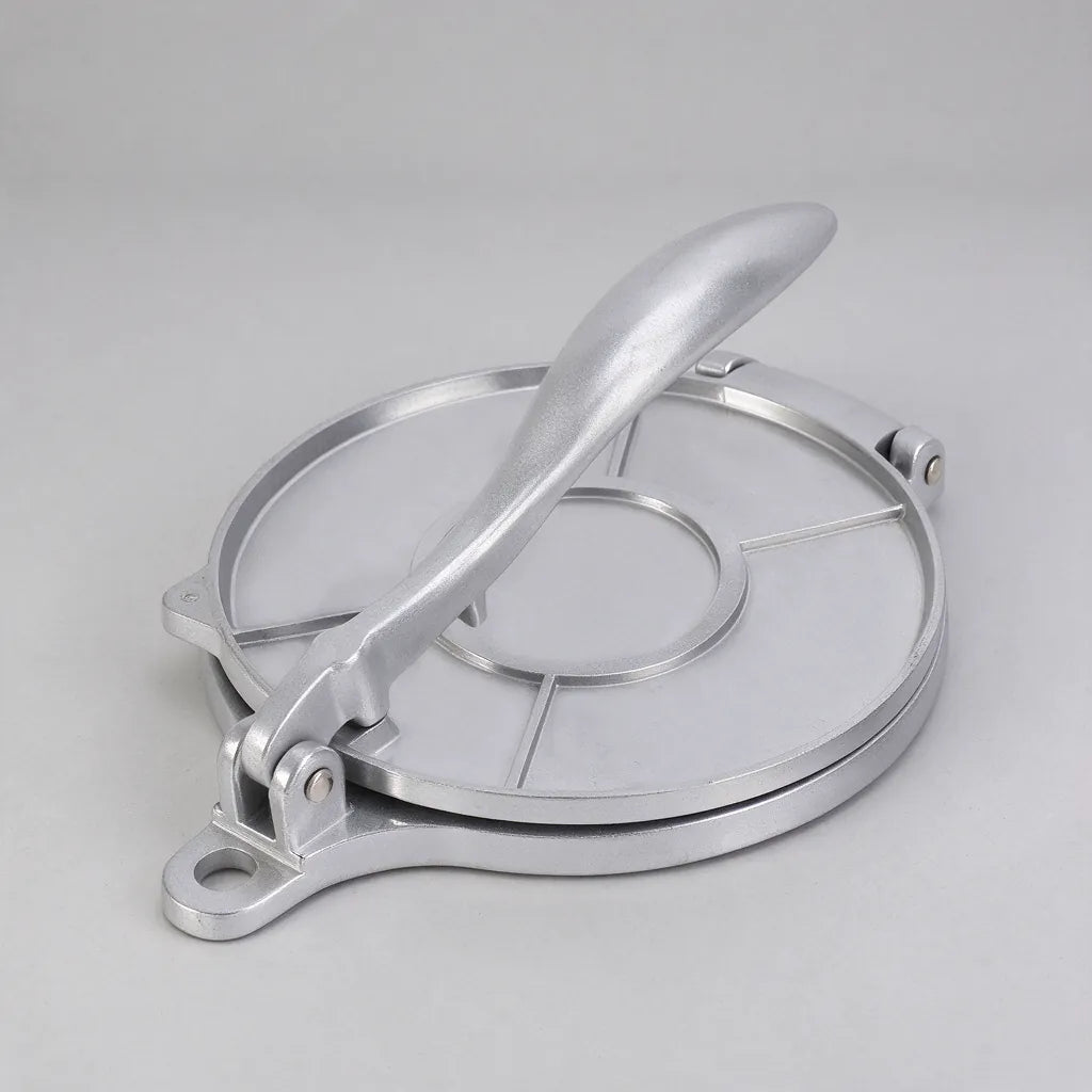 One silver aluminum tortilla press with the lever closed on a grey surface