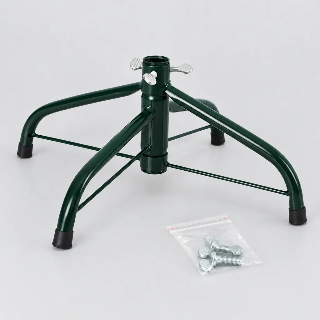 Dark green four-leg metal Christmas tree stand with a bag of wing screws on a grey surface