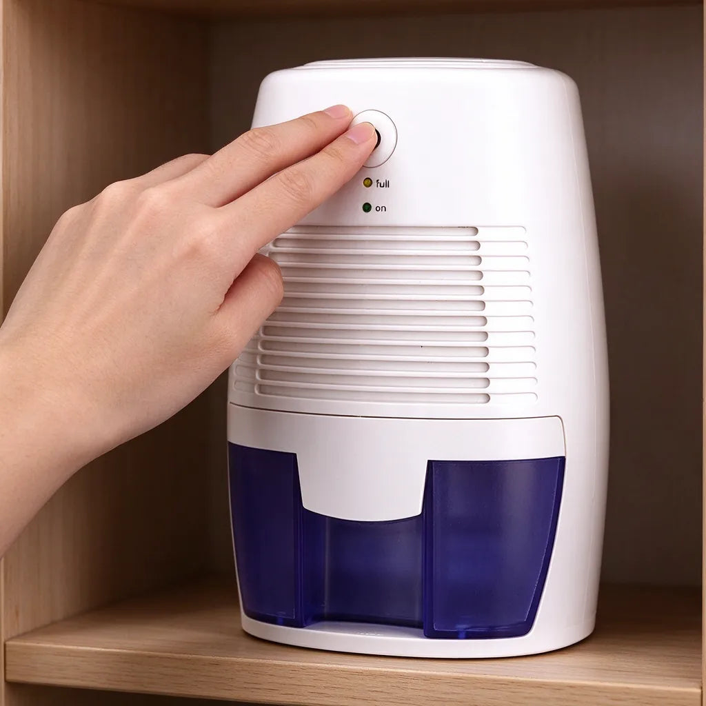 Hand pressing the power button of a small dehumidifier for a wardrobe