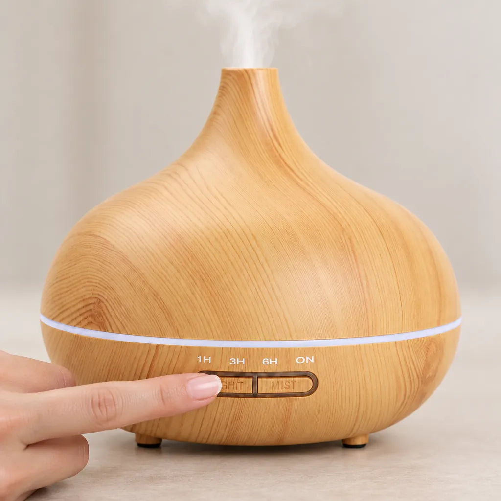 Hand pressing the button on a light wood grain ultrasonic essential oil diffuser with mist rising