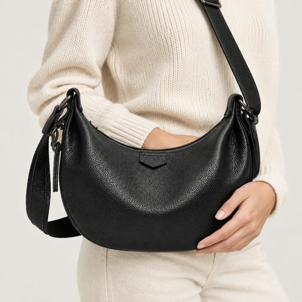 Woman wearing a black leather shoulder bag crossbody with her hand resting on it
