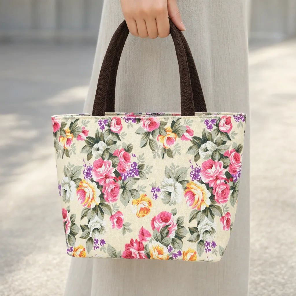 Hand carrying a cream mini canvas tote bag with a rose print