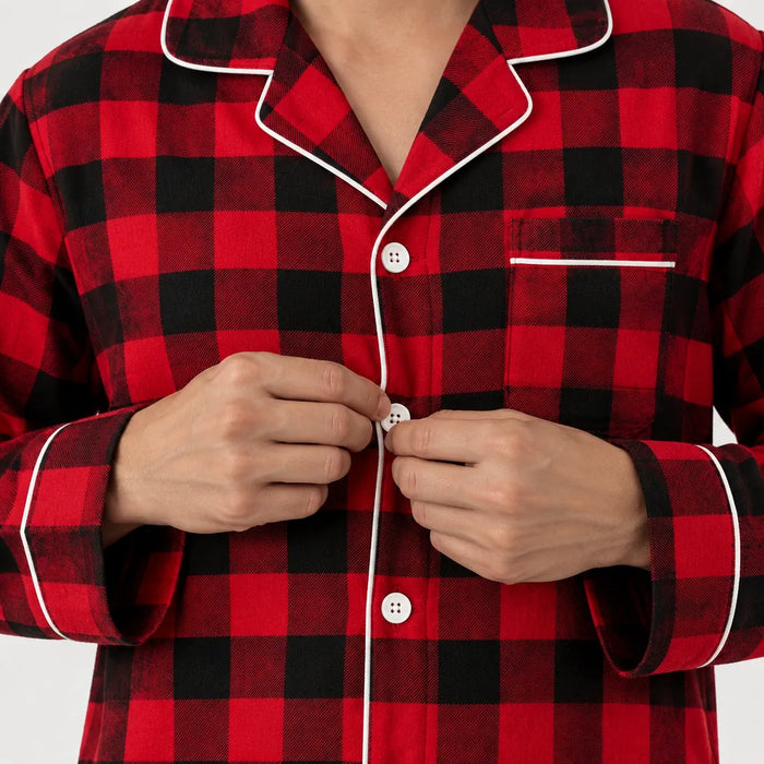Hands buttoning a red and black plaid pajama shirt with white piping
