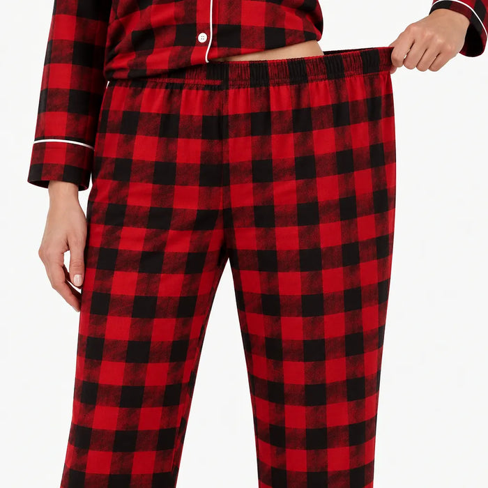 Person pulling on the elastic waist of red and black plaid pajama pants
