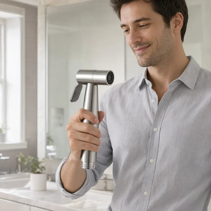 Smiling man in a bright bathroom holding a stainless steel handheld bidet sprayer