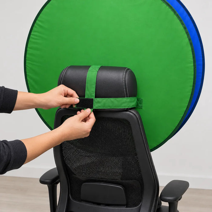 Hands fastening the strap of a pop up green screen around an office chair back