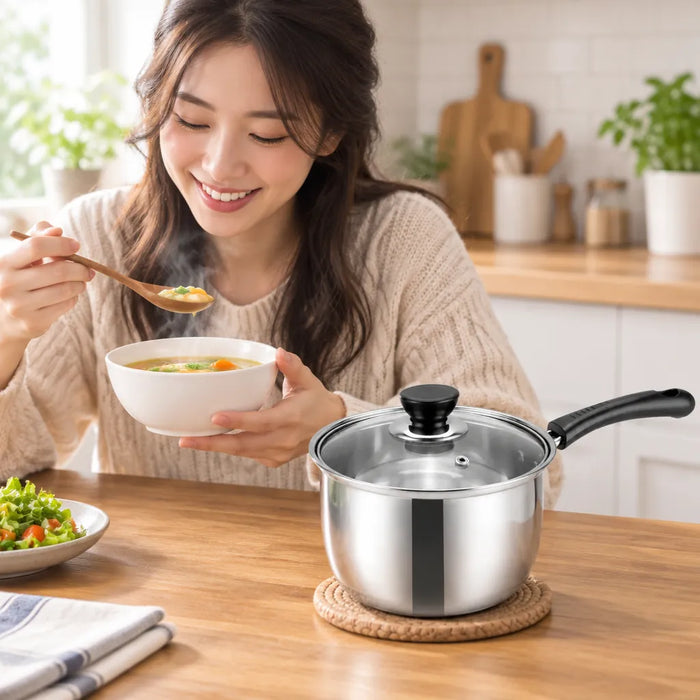 Mujer sonriendo con un plato de sopa caliente y una cacerola de acero inoxidable en la mesa