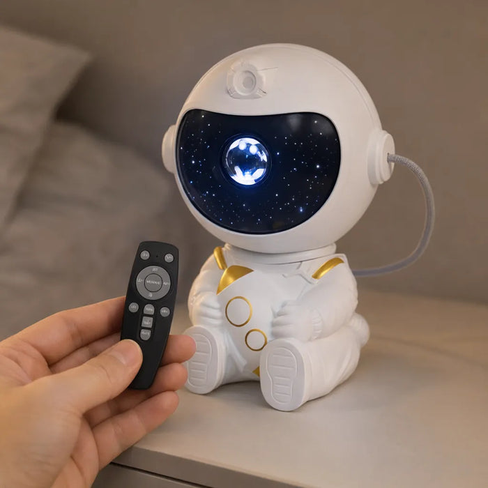 Mano apuntando el control remoto al proyector de astronauta en un buró