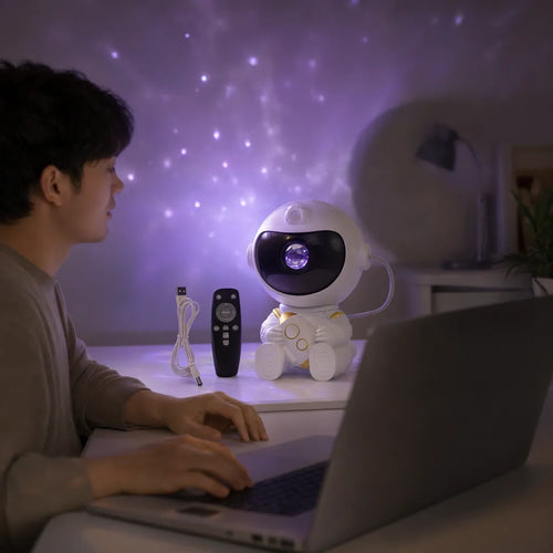 Hombre con laptop y un proyector de astronauta con luz morada sobre el escritorio