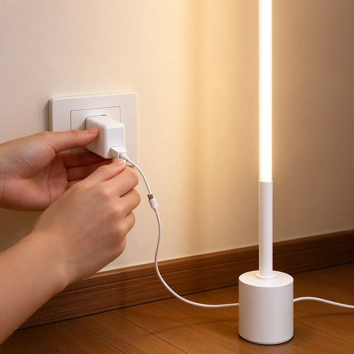 Mano conectando el cable USB de una lámpara de pie LED delgada a un adaptador
