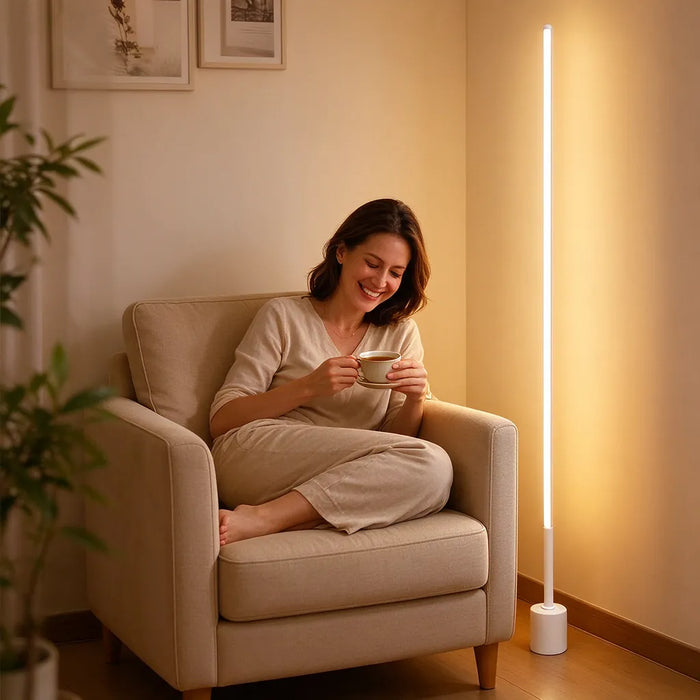 Mujer relajada en un sillón con té junto a una lámpara de pie LED encendida