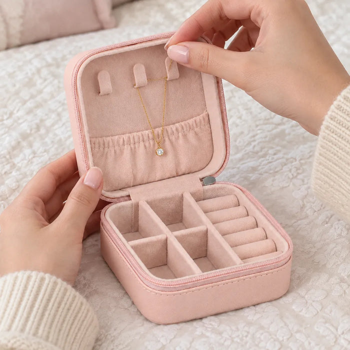 Hands hanging a gold necklace on a tab inside the lid of a jewelry organizer