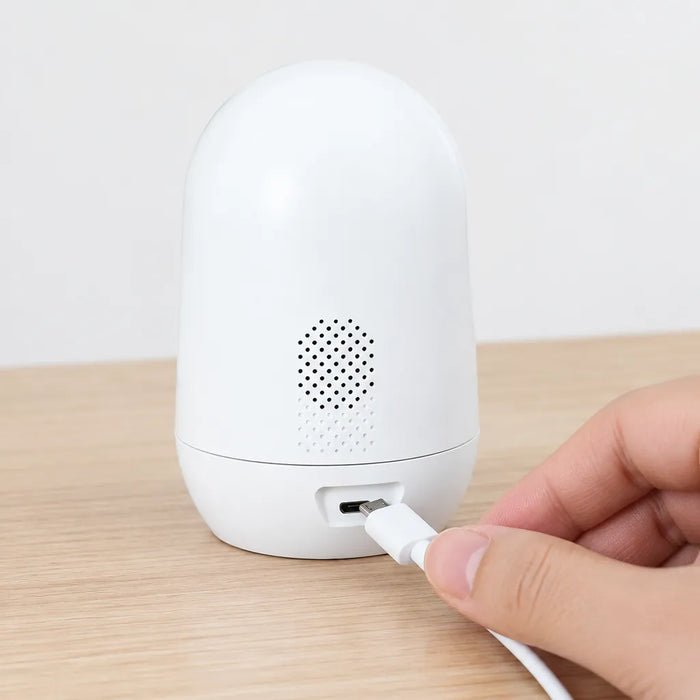 Hand plugging the USB cable into the back of the indoor security camera
