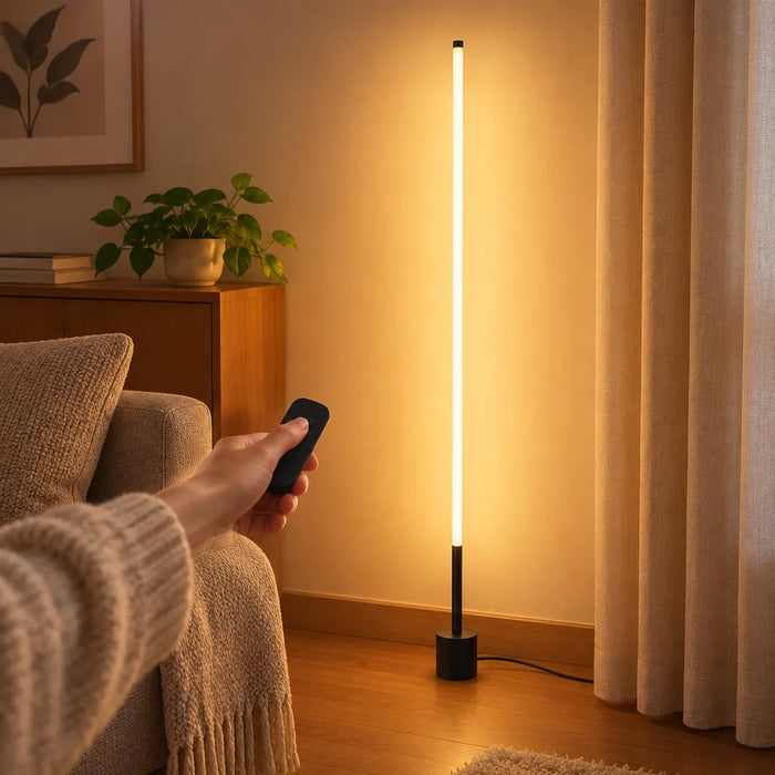 Main tenant une télécommande pour allumer un lampadaire LED mince dans un salon
