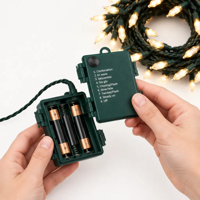 Hands inserting AA batteries into the battery box of outdoor Christmas lights