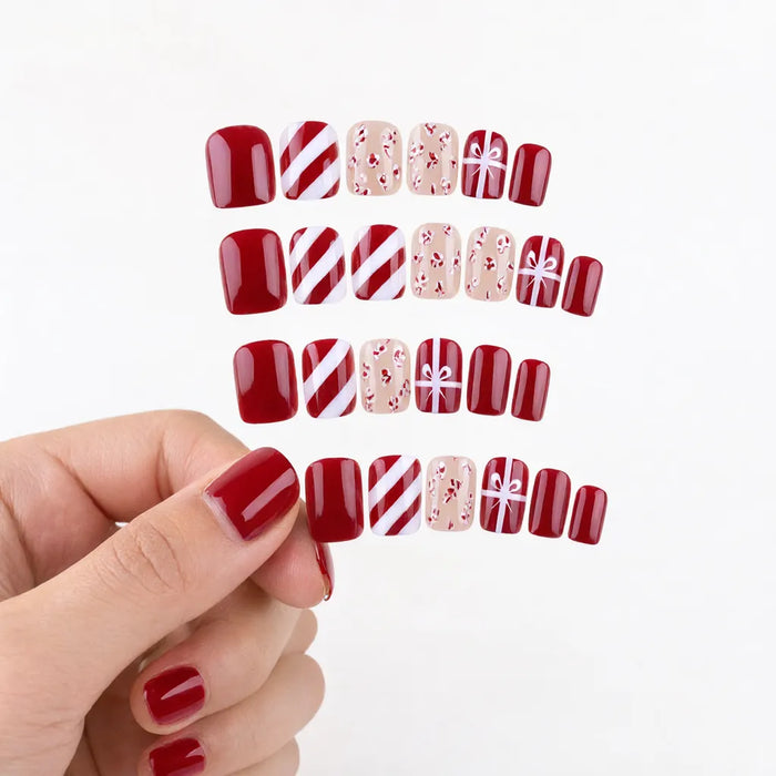 Hand wearing short square red press-on nails, thumb holding one fingertip down, fake nails christmas