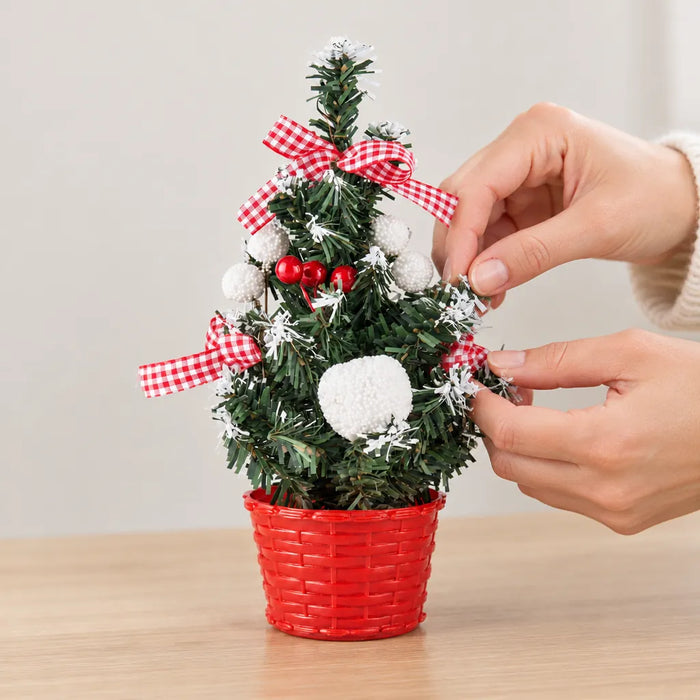 Finger fächern die verschneiten Zweige eines Tischweihnachtsbaums auf