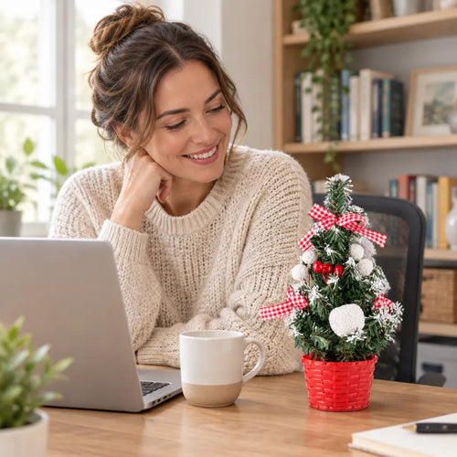 Frau arbeitet am Laptop, daneben ein kleiner Weihnachtsbaum mit roten Schleifen auf dem Schreibtisch