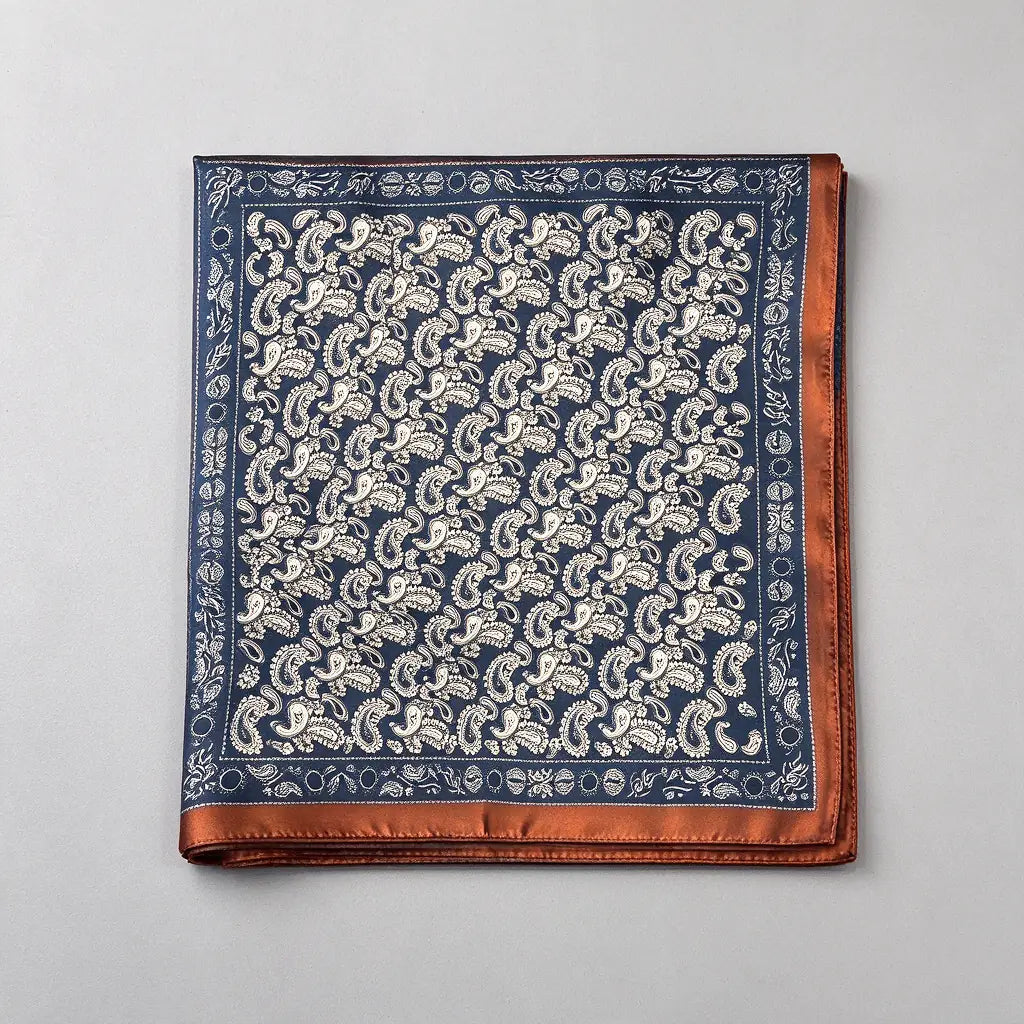 One folded navy paisley satin-finish scarf on a grey surface