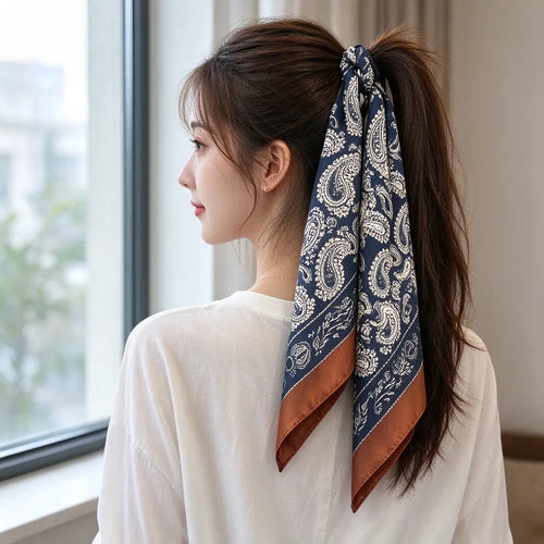 Kvinne sett bakfra med paisley hårskjerf bundet rundt hestehalen ved et vindu