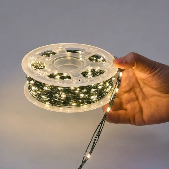 Hand unspooling green wire LED Christmas lights from the clear reel
