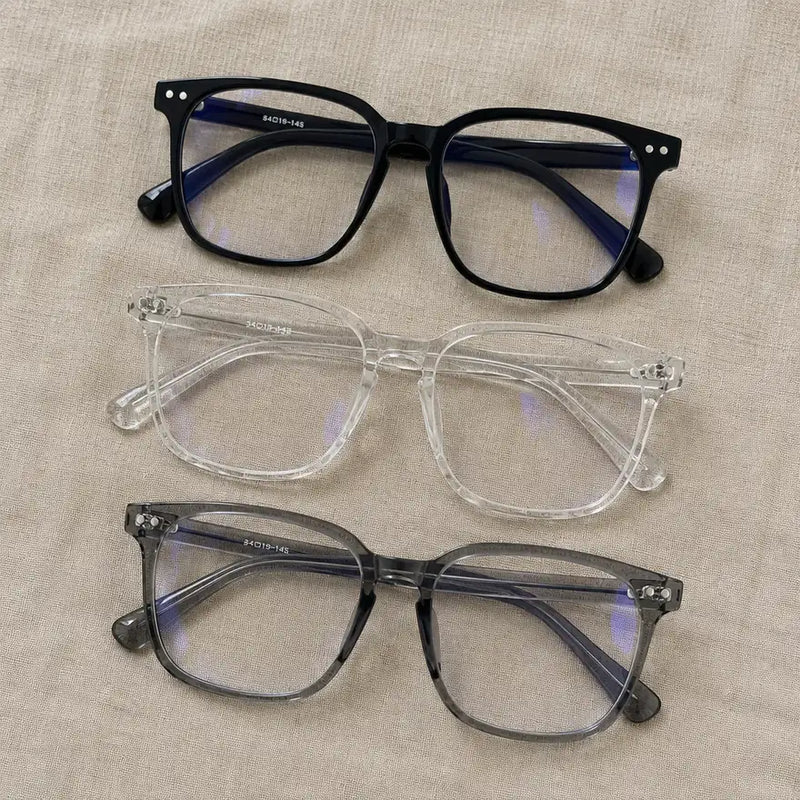 Black, clear and smoky grey square blue light glasses side by side on linen