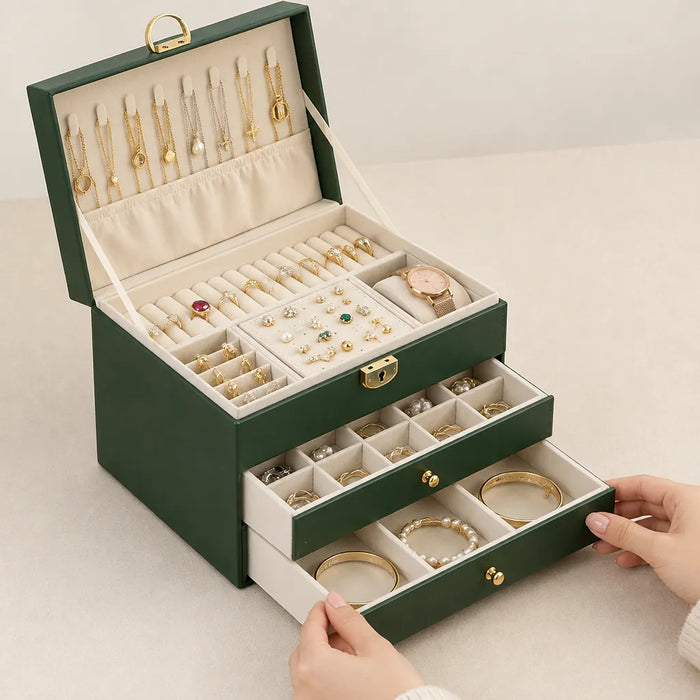 Hands pulling out a drawer of a green jewellery box with drawers full of rings and bracelets