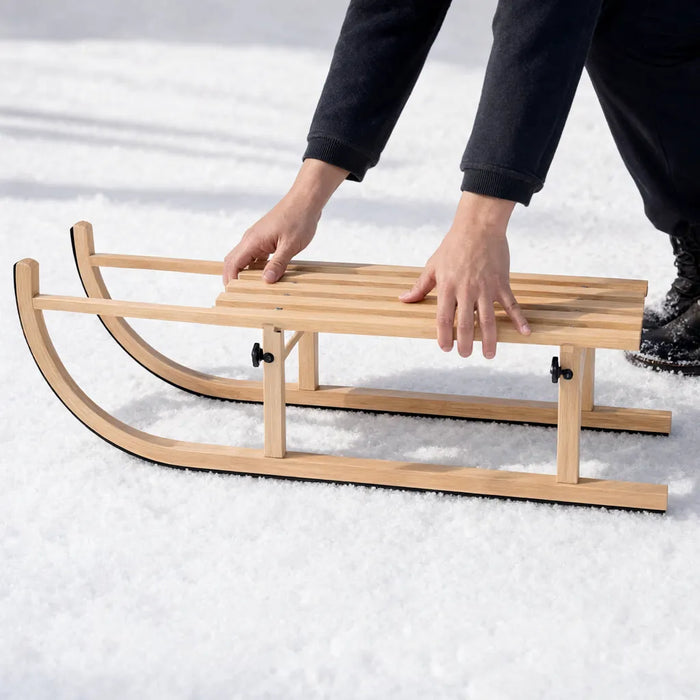 Hände klappen einen klappbaren Holzschlitten im Schnee auf