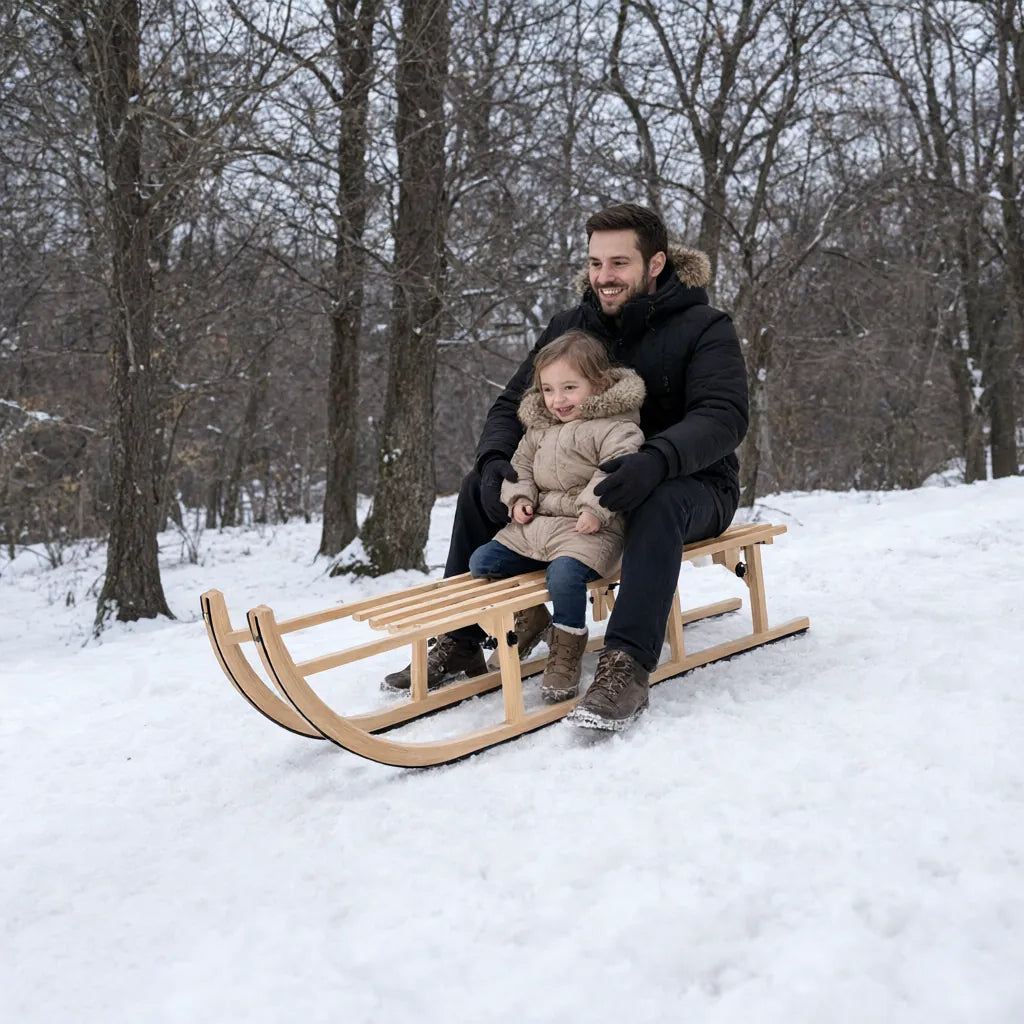 Father and young daughter sitting on a wooden sled on a snowy park hill