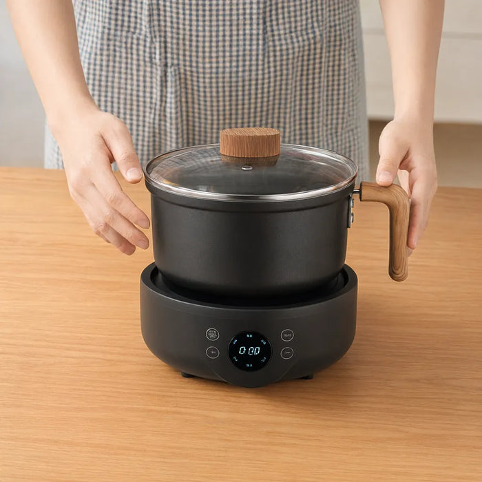 Hände setzen den schwarzen Topf auf die Basis des elektrischen Hot Pots