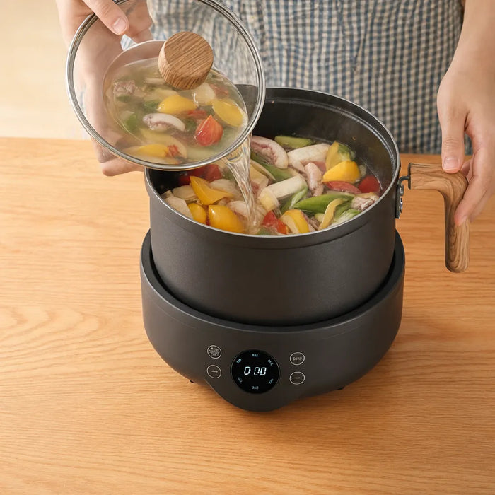 Brühe wird über Gemüse im elektrischen Hot Pot für Fondue Chinoise gegossen