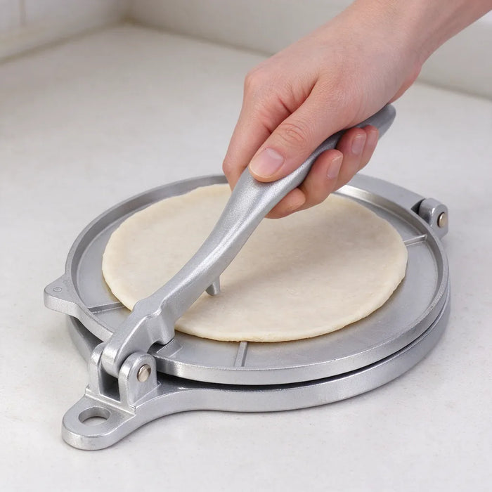 Hand pulling the lever of a tortilla press down to flatten dough into a round