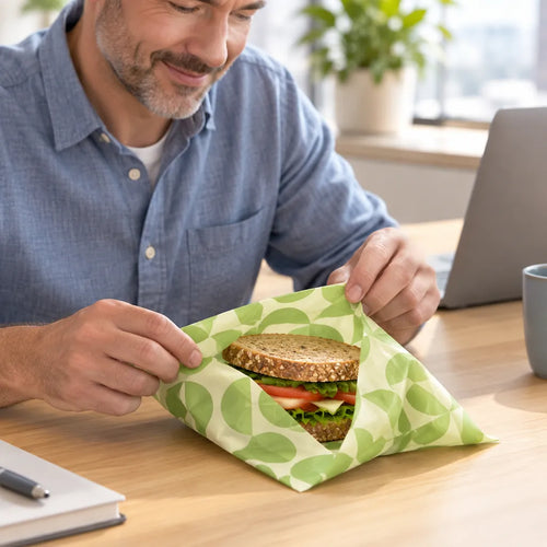 Man at his office desk unwrapping a sandwich from a beeswax sandwich wrap