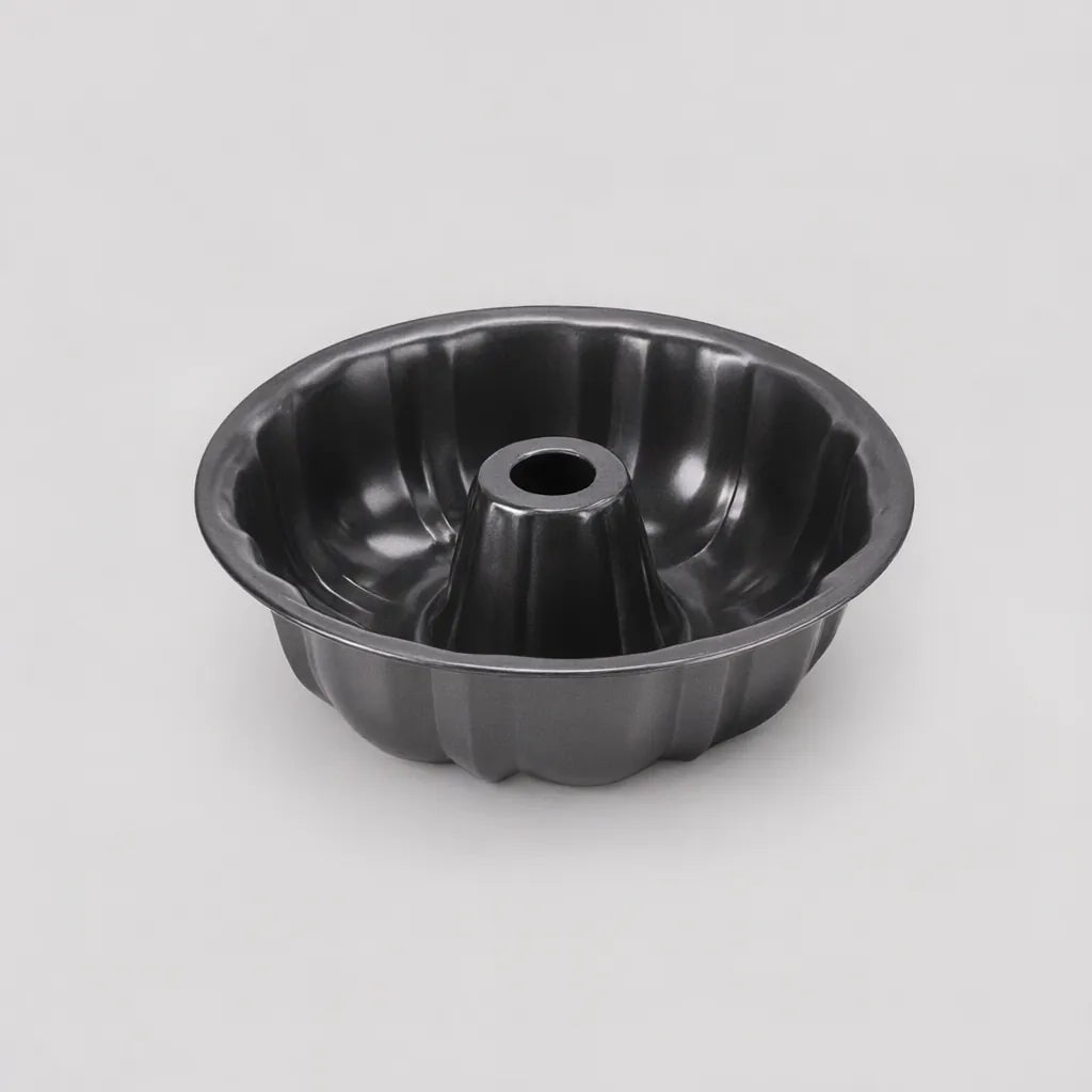 One black non-stick fluted ring cake pan on a light grey surface