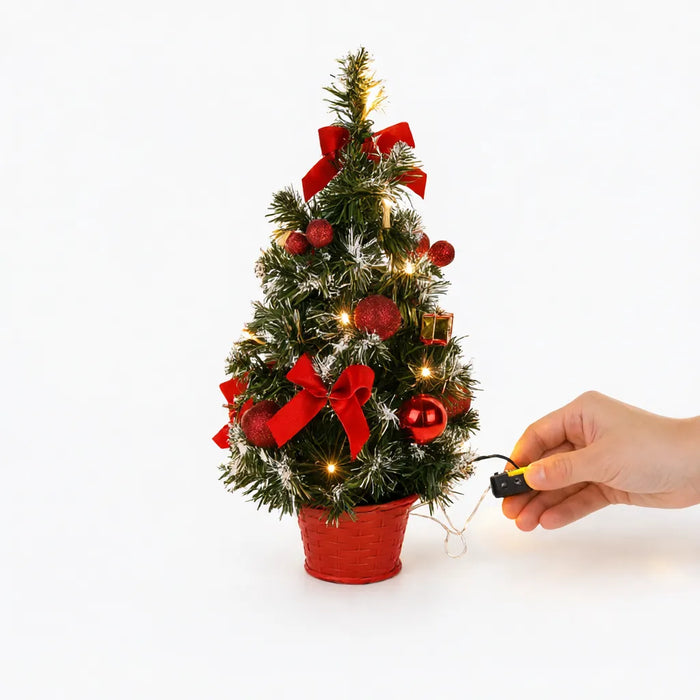 Mano encendiendo la caja de pilas de un árbol de Navidad pequeño con luces