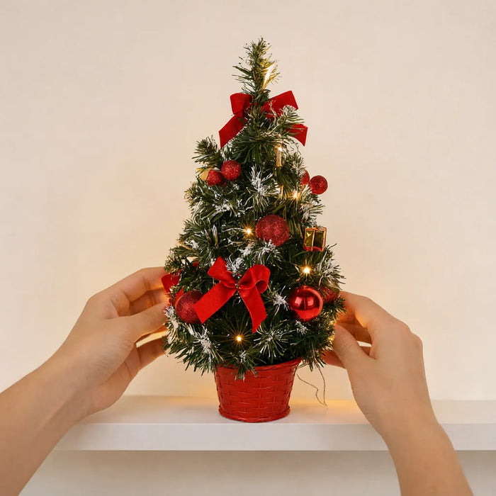 Manos colocando un mini árbol de Navidad con luces en una repisa blanca