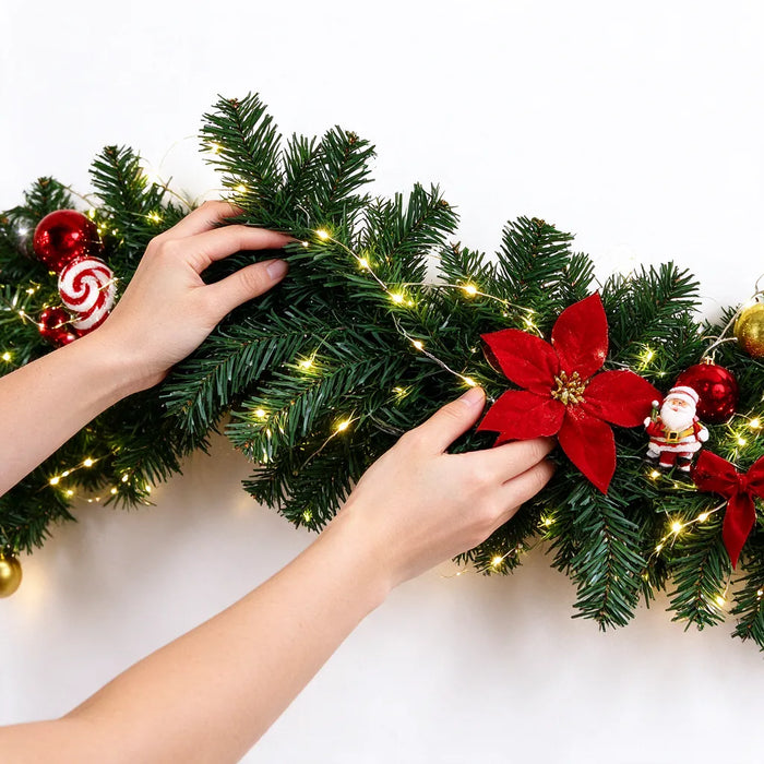 Hands fanning out the branches of a pre-lit christmas garland with a red poinsettia