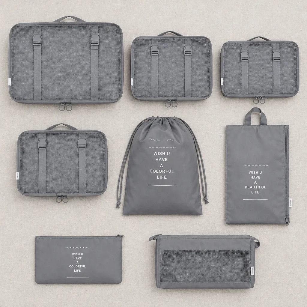 Grey travel packing cubes set laid flat: 4 mesh-top cubes, laundry bag, zip pouch, toiletry pouch and shoe bag
