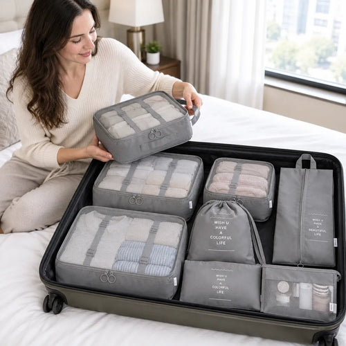 Woman in a hotel room lifting a grey packing cube out of her organized suitcase