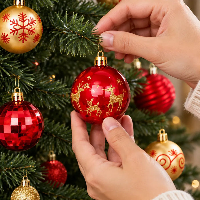 Hände hängen eine rote Weihnachtskugel an einen geschmückten Tannenzweig
