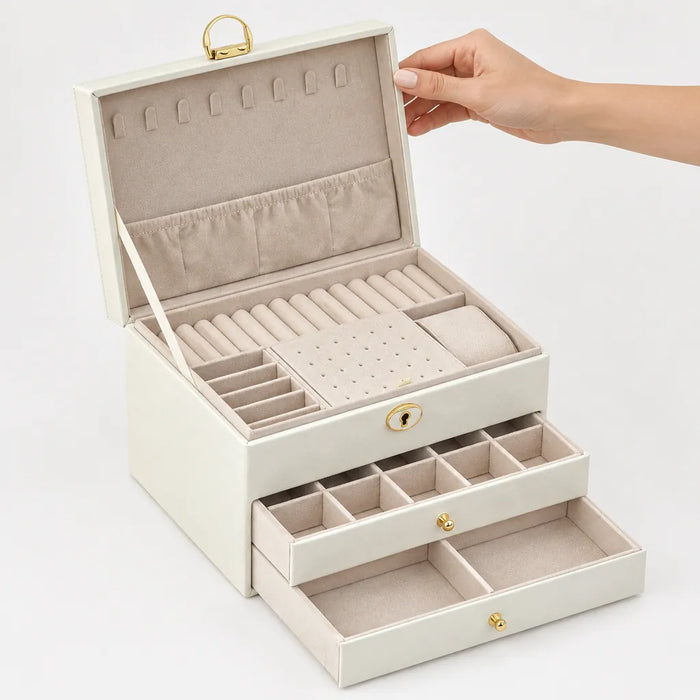 Hand hebt den Deckel eines cremeweissen Schmuckkästchens mit Ringschlitzen und Kettenhaken