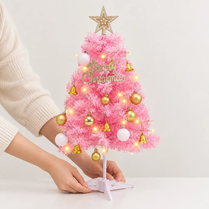 Hands setting a small pink Christmas tree on its stand on a white table